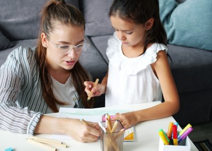 Happy family daughter and mother drawing picture at table in apartment, joyful kid is smiling enjoying hobby and mother's help. People and lifestyle concept.